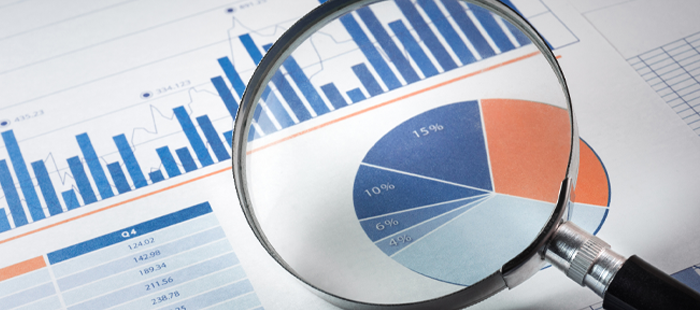 Closeup of magnifying glass over a document with data charts