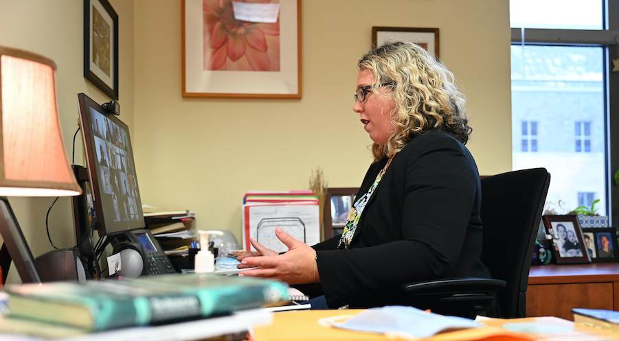 woman professort sitting at her desk, communicating with students over her computer