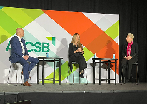 three speakers give presentation on stage sitting in stools