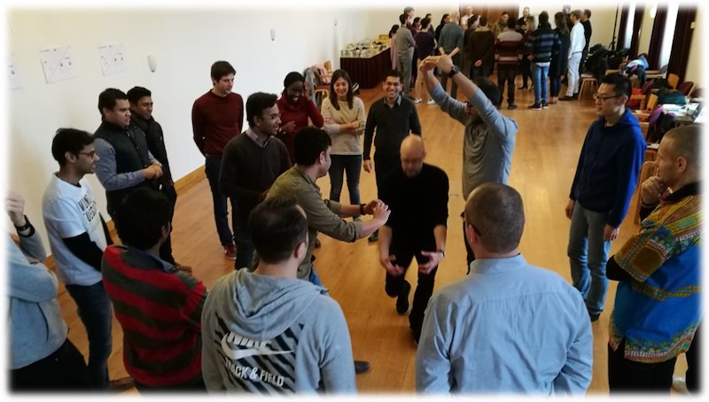 Classroom of business students gathers around to learn dance steps from professor