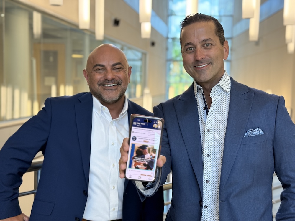 Two men--Angel Burgos and Sergio Tigera--smile at the camera. One is holding a phone which shows an image of an app designed for students.