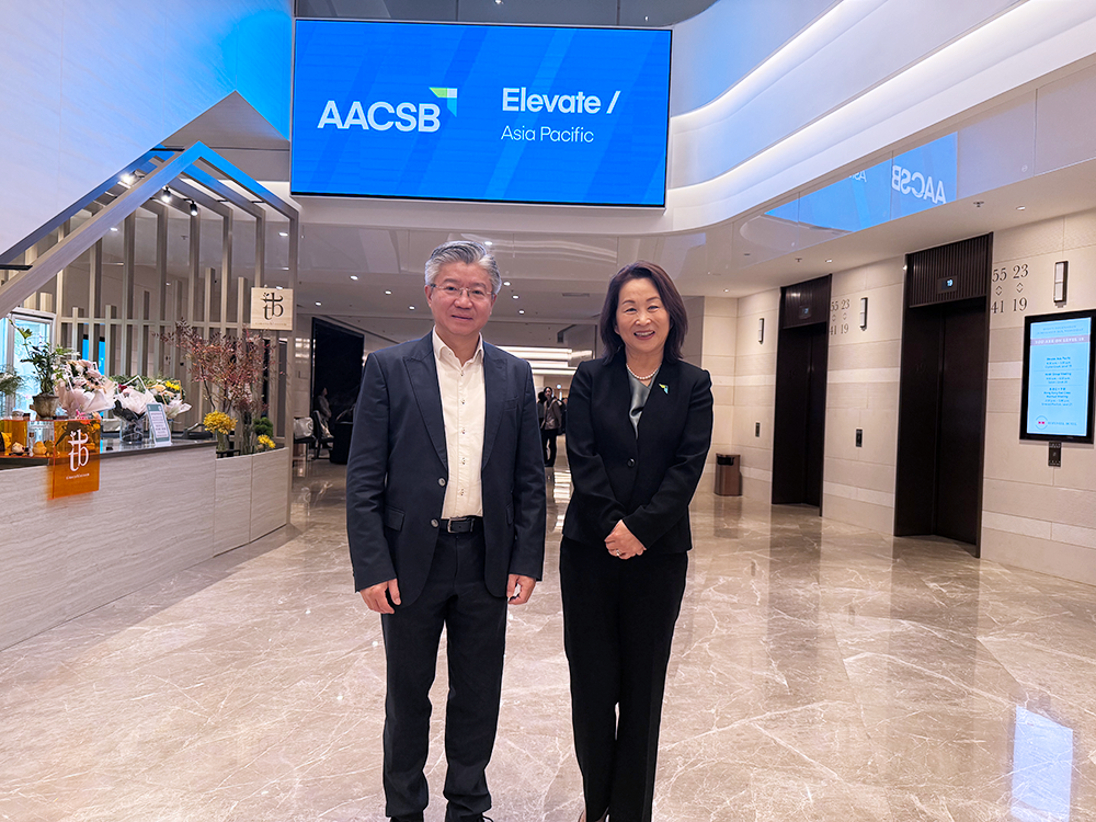 Xiongwen Lu and Lily Bi stand together smiling, with AACSB's Elevate: Asia Pacific Conference signage in the background.