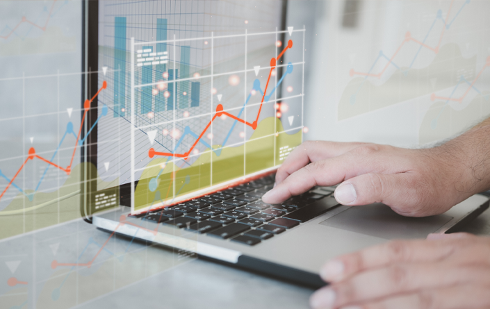 Hands using a laptop with colorful data trend lines extending across and beyond the screen