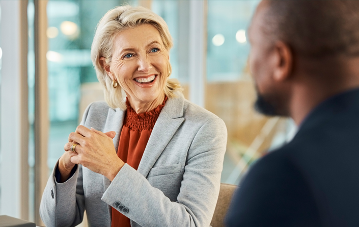 Mature Caucasian businesswoman smiles in discussion with a mature African American male